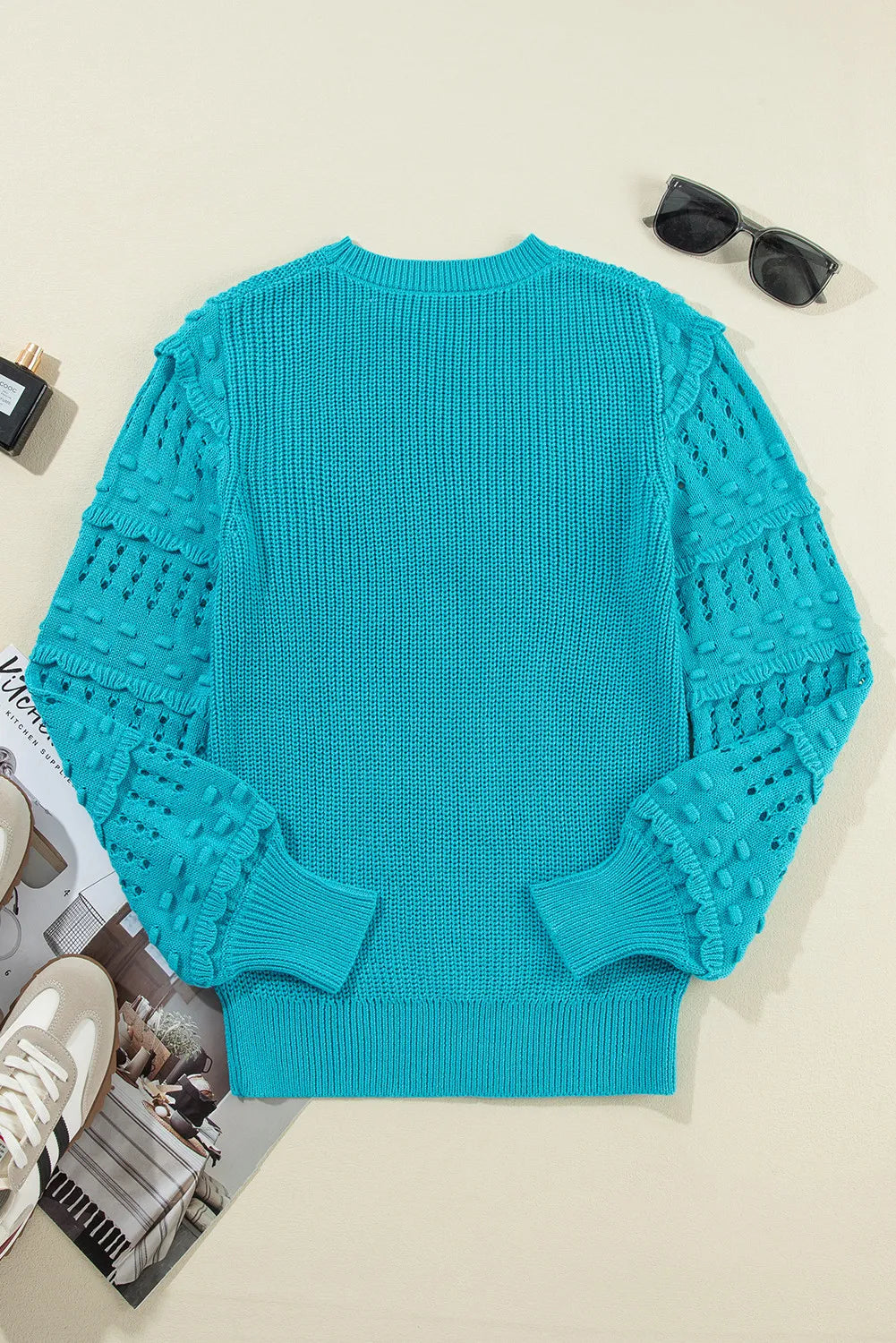 Turquoise knit sweater with textured cutout sleeves and crew neck.