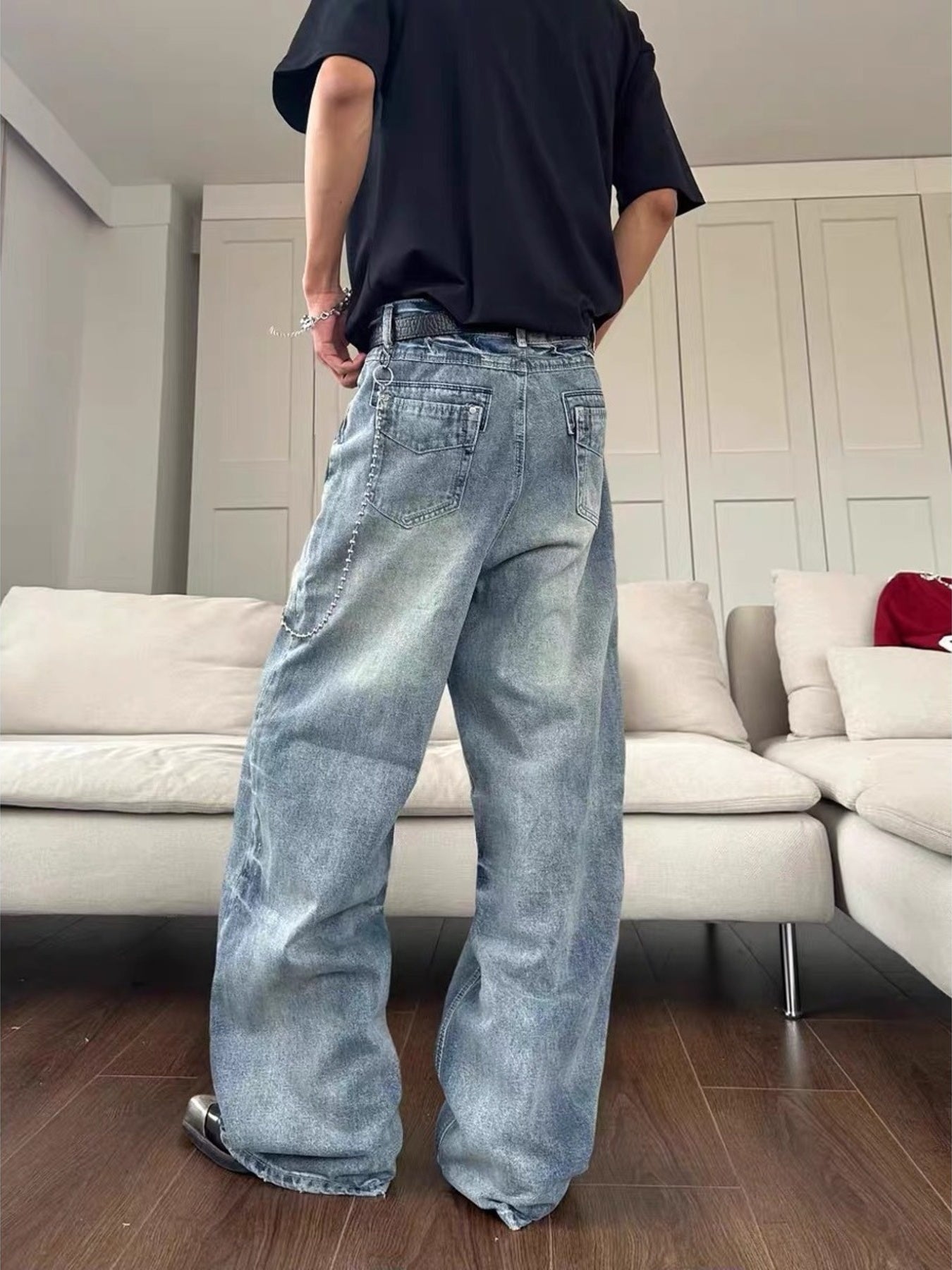 Men's light blue wide leg jeans with distressed details and chain accent.
