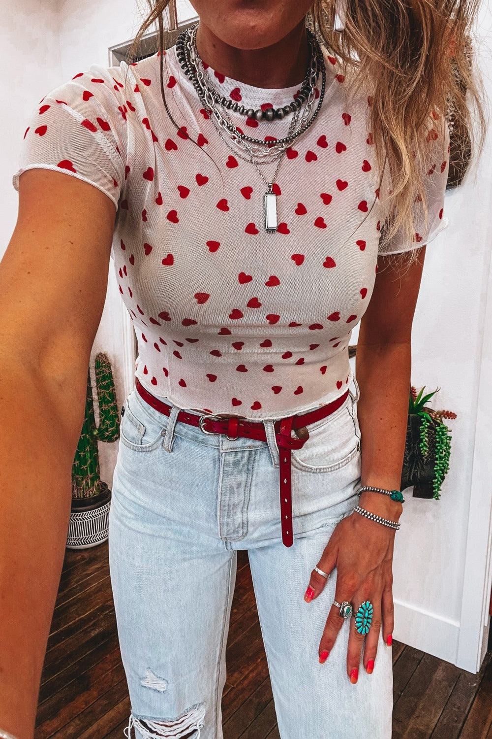 White sheer t-shirt with red heart print, short sleeves, and a fitted cut.