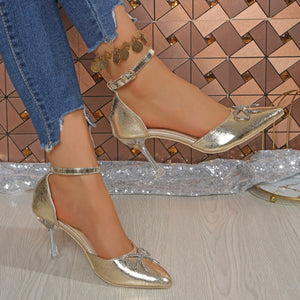 Gold rhinestone bow pointed toe heels with clear heel and ankle strap.