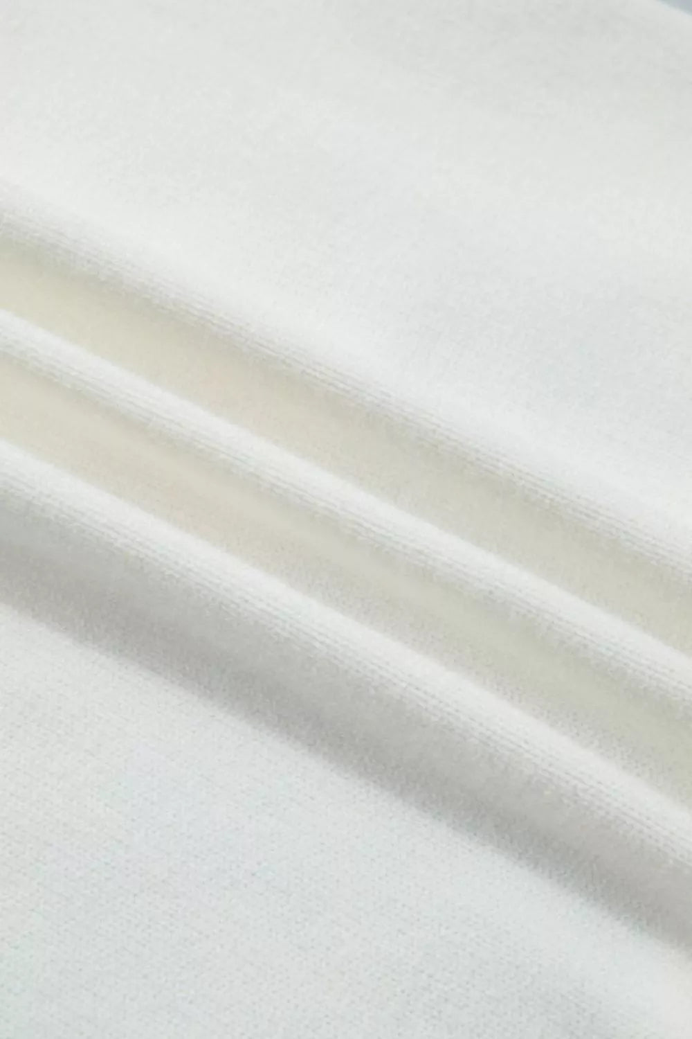 White knit sweater vest fabric detail showing ribbed texture and soft material.