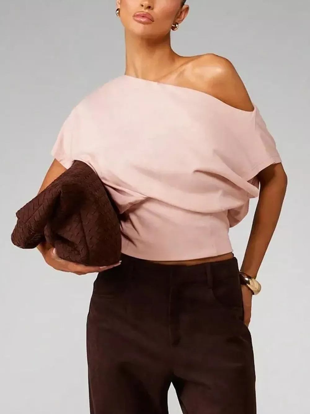 Pink asymmetrical crop t-shirt with draped fit and off-the-shoulder neckline.