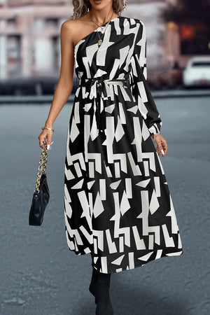 Black and white geometric print asymmetric maxi dress with belt and one long sleeve.