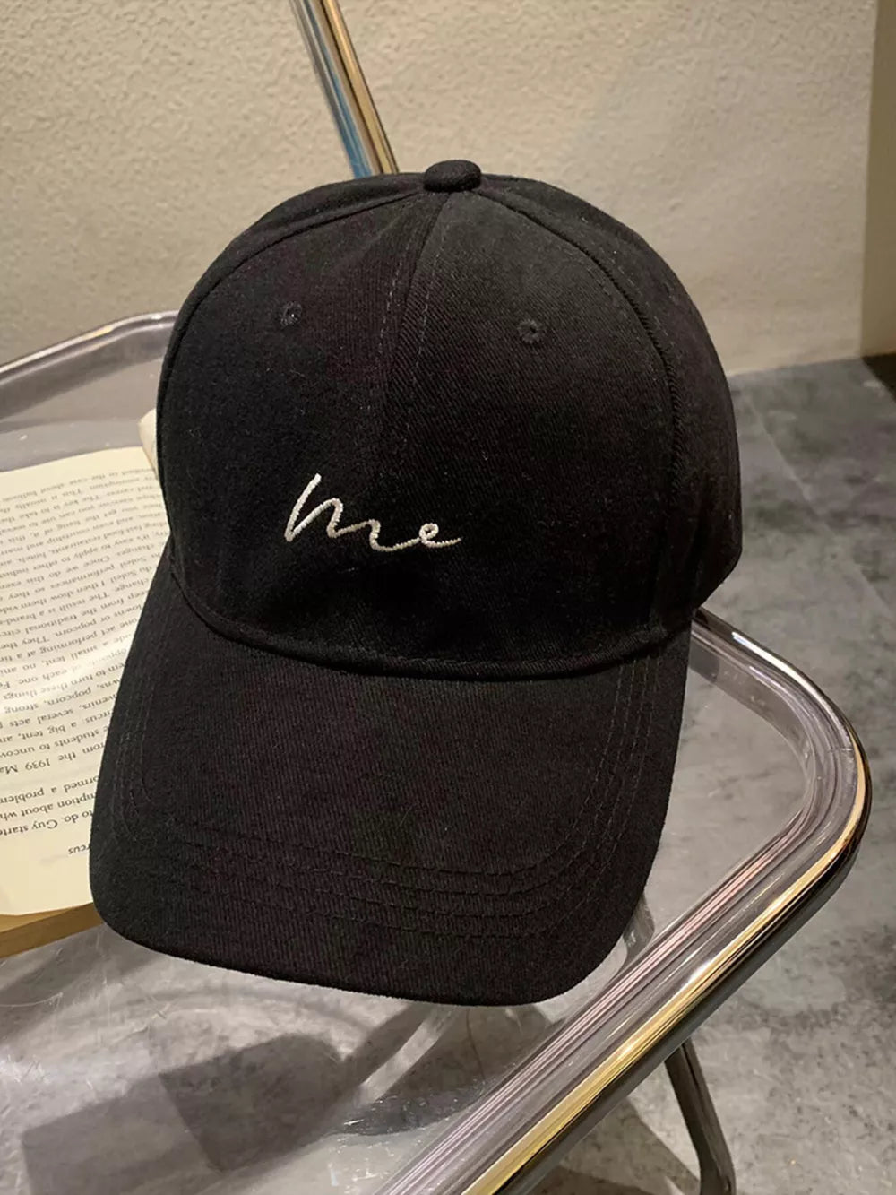 Black cotton baseball cap with curved brim and embroidered "me" detail
