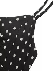 Black polka dot dress with thin spaghetti straps and ruffled hem detail.