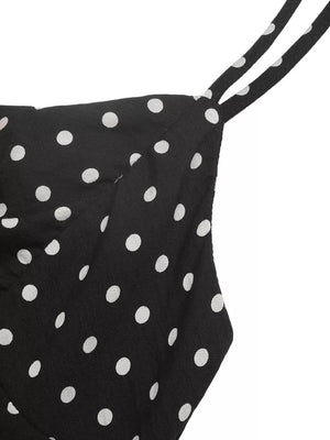 Black polka dot dress with thin spaghetti straps and ruffled hem detail.