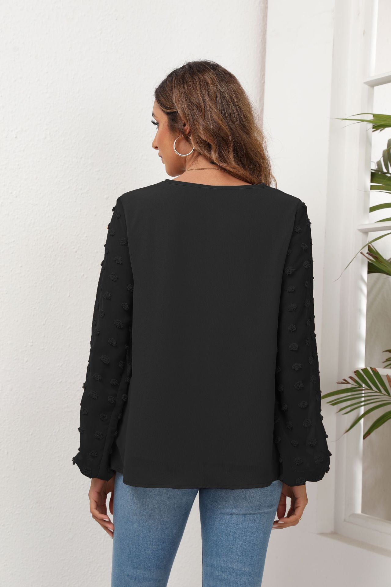 Black V-neck blouse with textured pom-pom balloon sleeves.