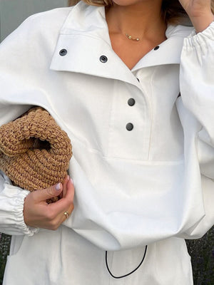 White two-piece set with snap details, collared neckline, and elastic cuffs.