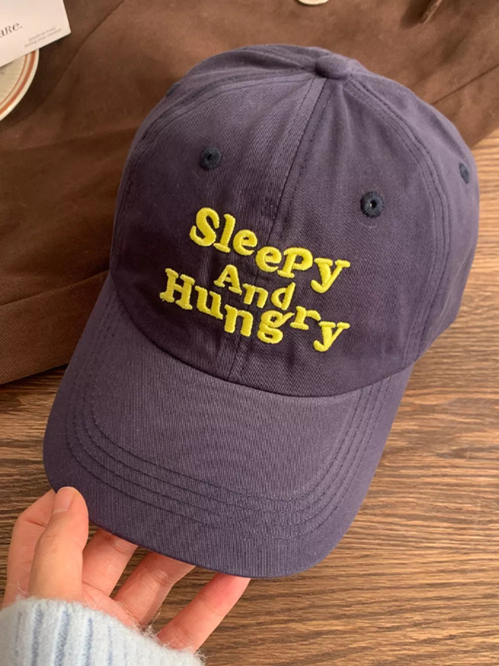 Navy blue cotton baseball cap with yellow embroidered Sleepy And Hungry text