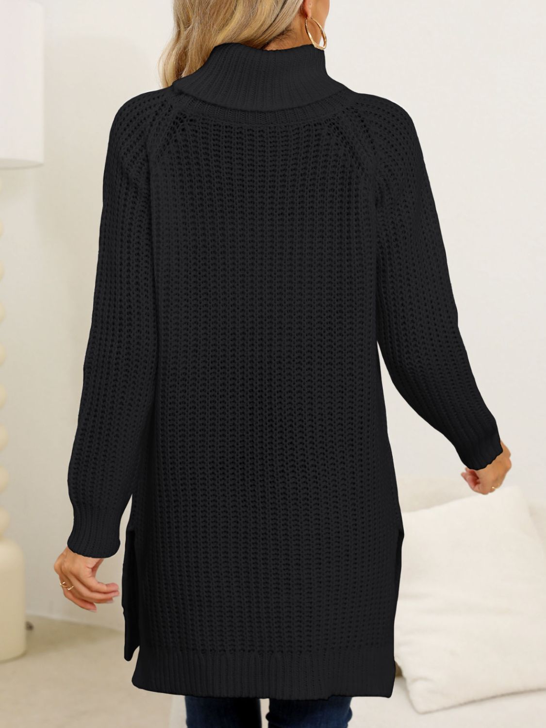 Black knit turtleneck sweater with an asymmetric hemline and side slits.