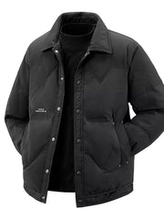 Black padded puffer jacket with button-down front and collar, styled over a turtleneck.