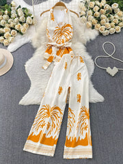 White polyester two-piece set with orange tropical print, halter top, belted detail, and wide-leg pants.