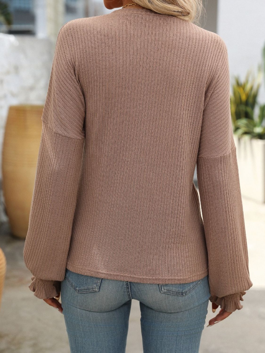 Textured ribbed knit blouse in brown with ruffled cuffs and long sleeves.
