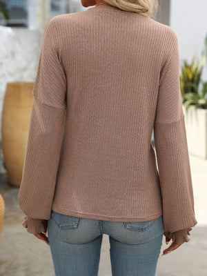 Textured ribbed knit blouse in brown with ruffled cuffs and long sleeves.
