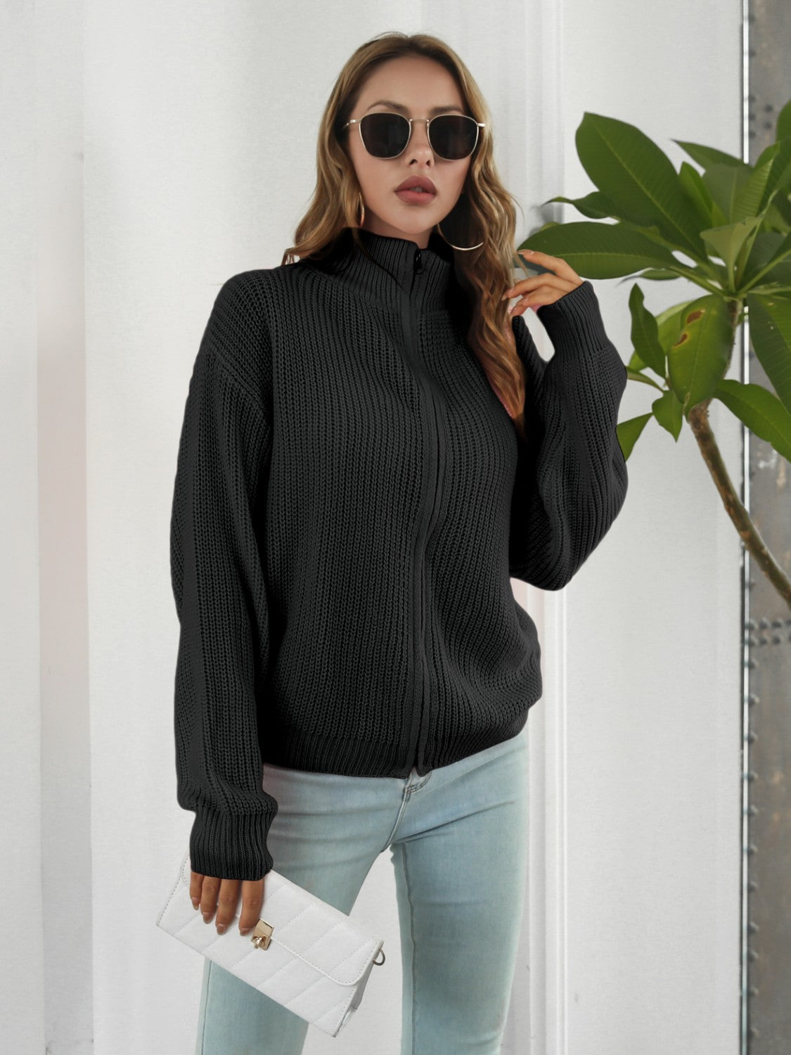 Black ribbed knit zip-up sweater with mock neck and long sleeves.