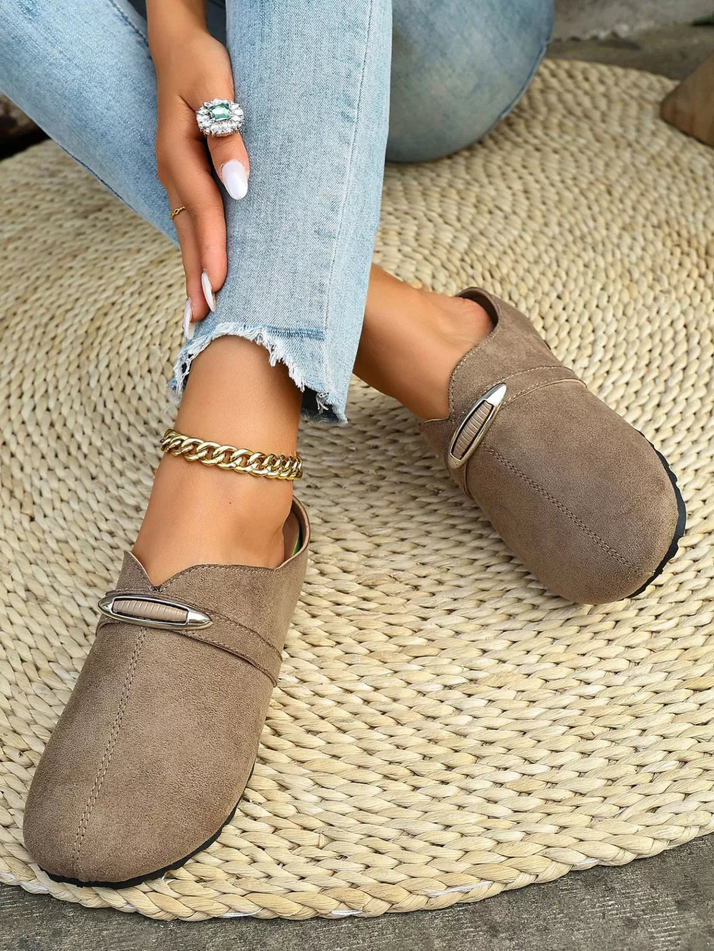 Brown slip-on flats with round toe and decorative buckle detail.