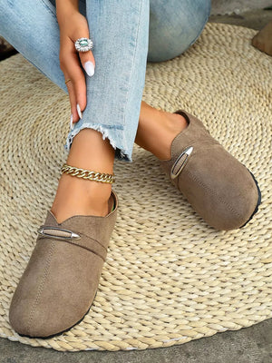 Brown slip-on flats with round toe and decorative buckle detail.