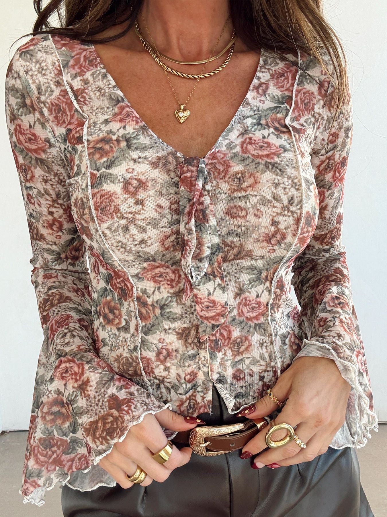 Charming floral mesh blouse with tie neck and ruffled bell sleeves.