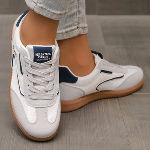 White and grey lace-up sneakers with navy blue accents and a gum sole.