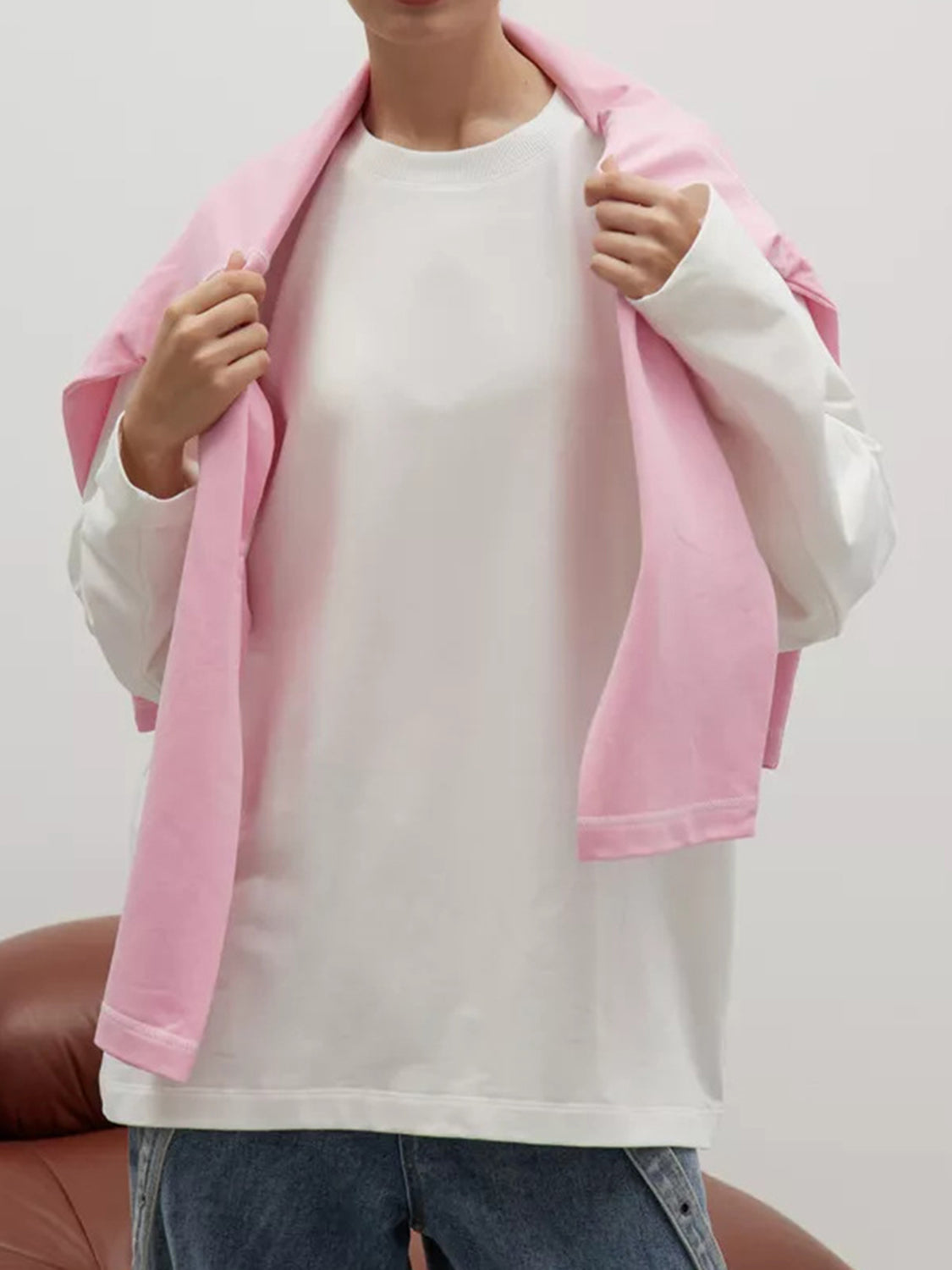 Oversized crewneck sweatshirt in white with pink draped over shoulders, long sleeves.