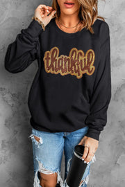 Black crewneck sweatshirt with sequin "thankful" graphic.