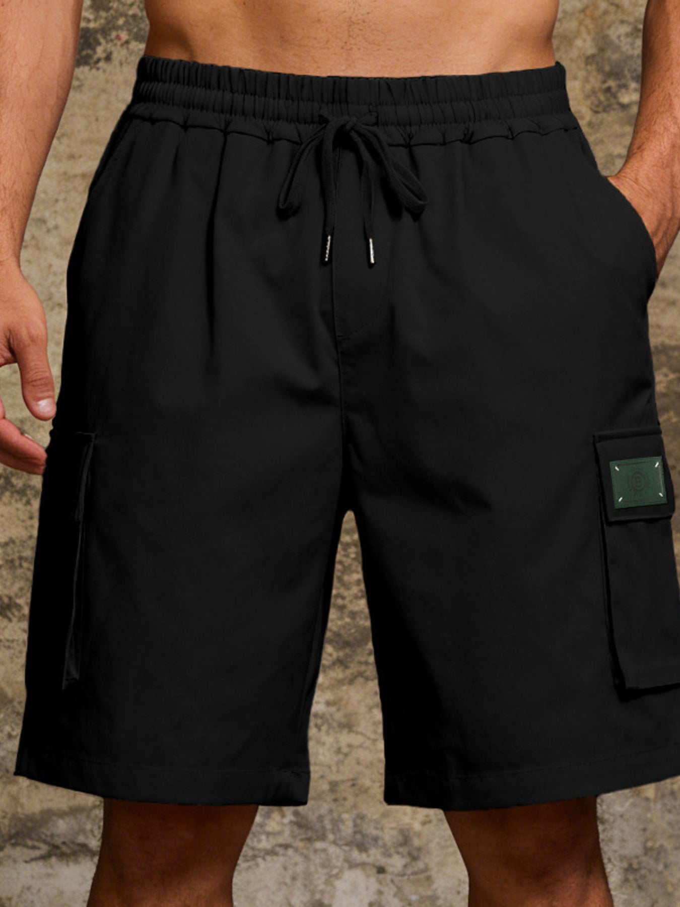 Black cargo shorts with drawstring waist and side cargo pocket with green patch detail.