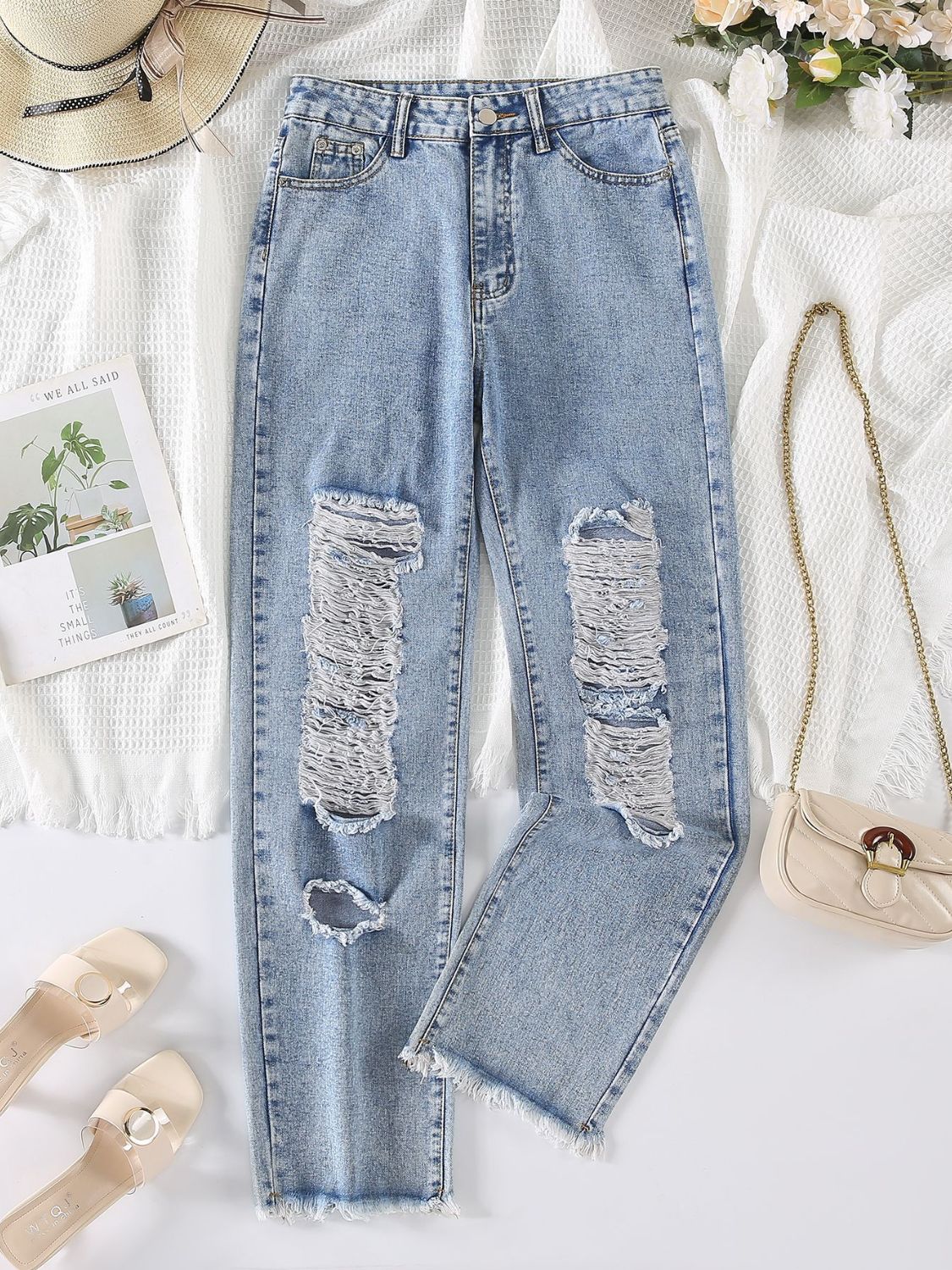 Light wash denim jeans with shredded knee detail and frayed hem