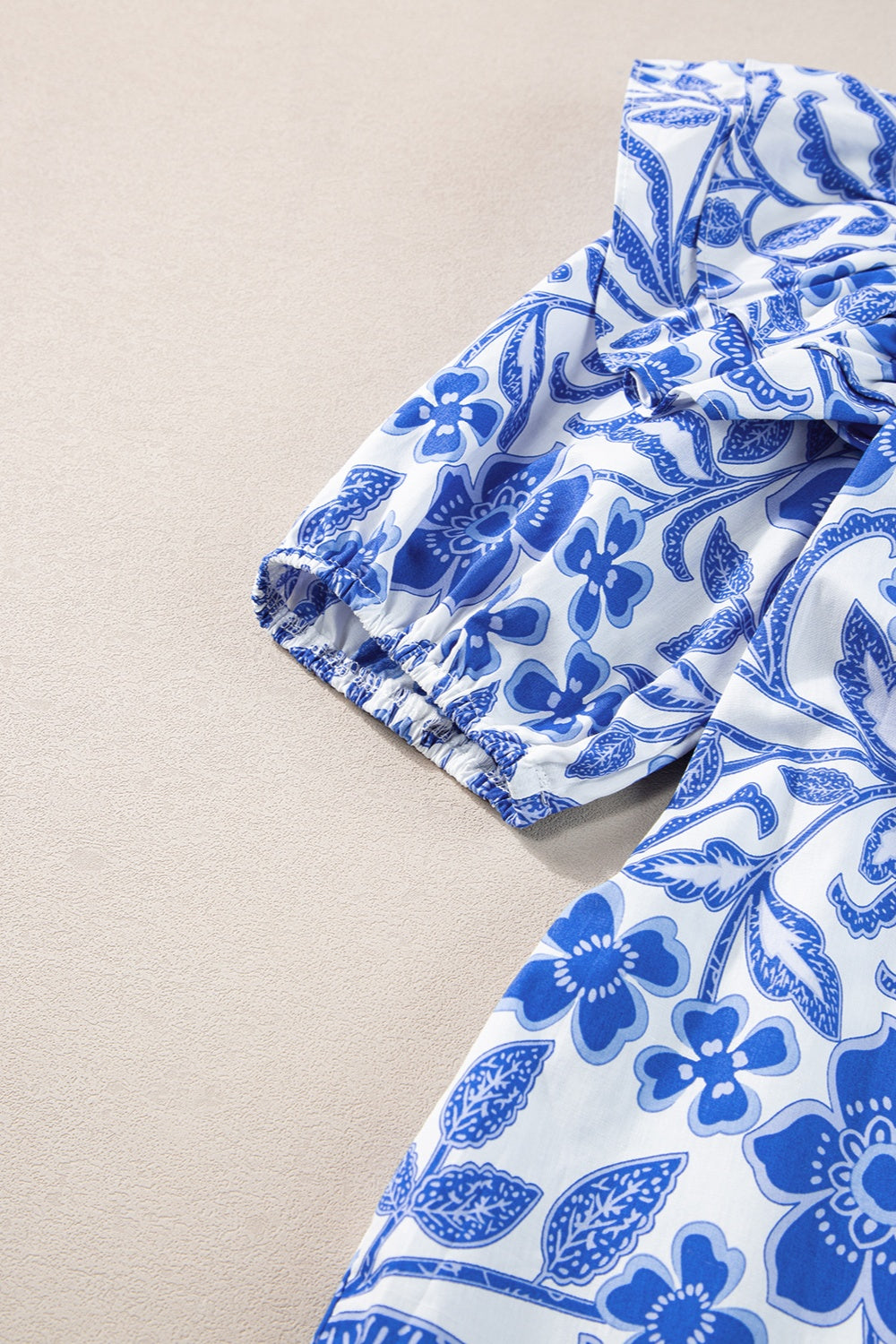 Blue floral print blouse with ruffled sleeves and elastic cuffs.