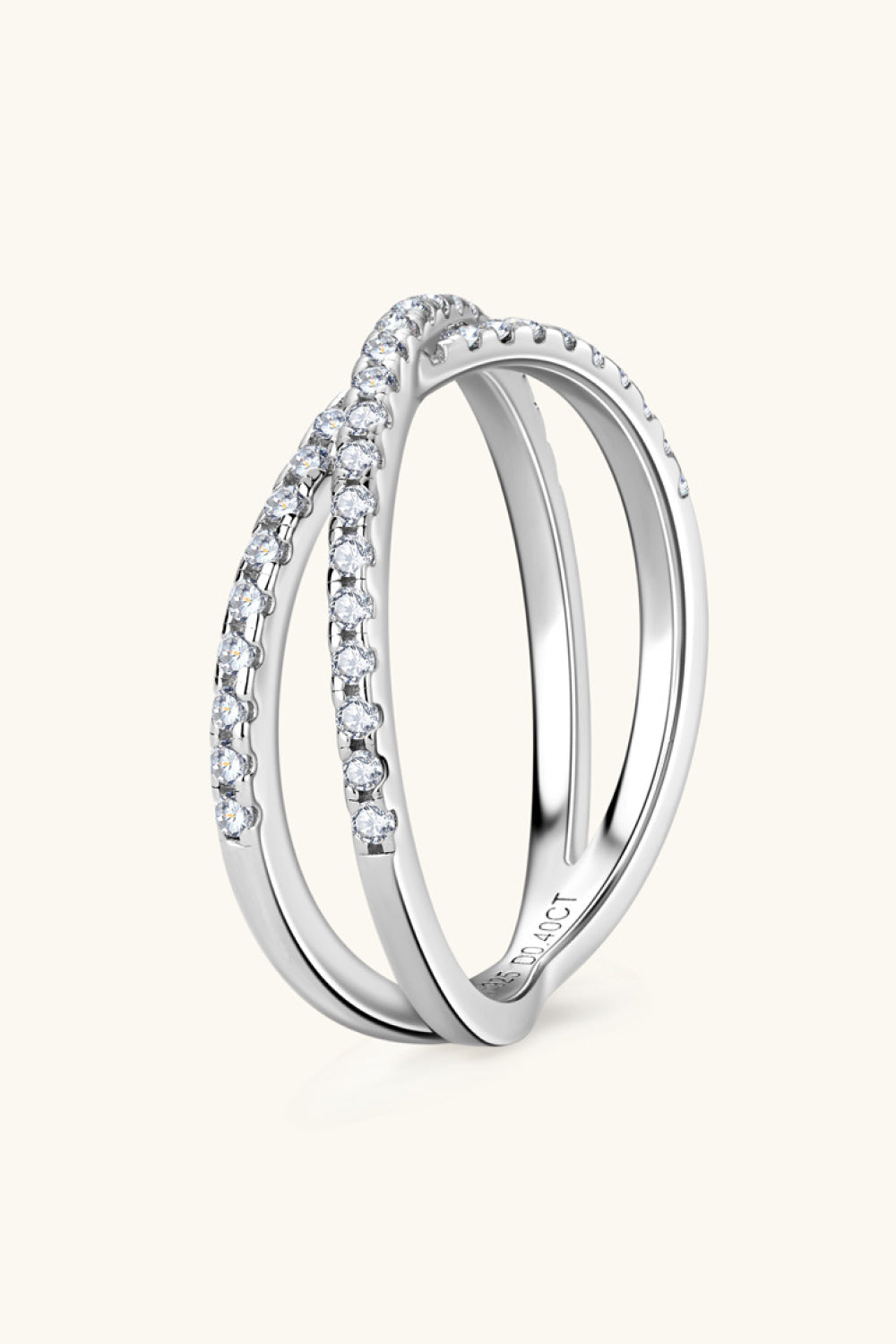 Silver pavé crossover band ring with two intertwined bands, detailed with small clear stones.