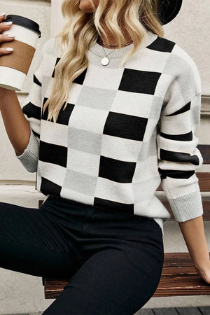 Black and white checkerboard knit pullover sweater with crew neck and long sleeves.