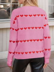 Pink knit sweater with red heart stripe pattern and crew neck.