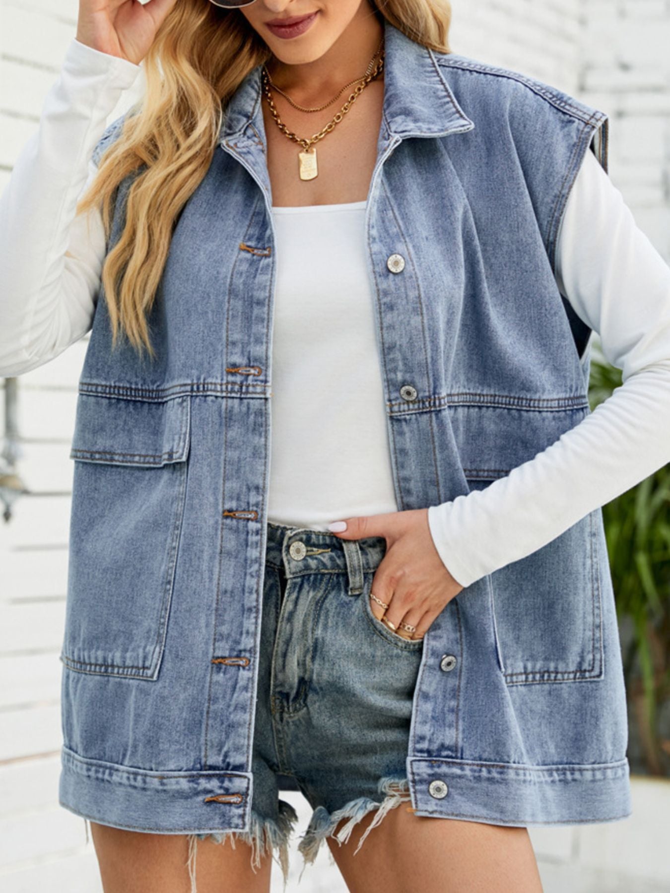 Sleeveless denim vest in light blue with button-down front and chest pockets.