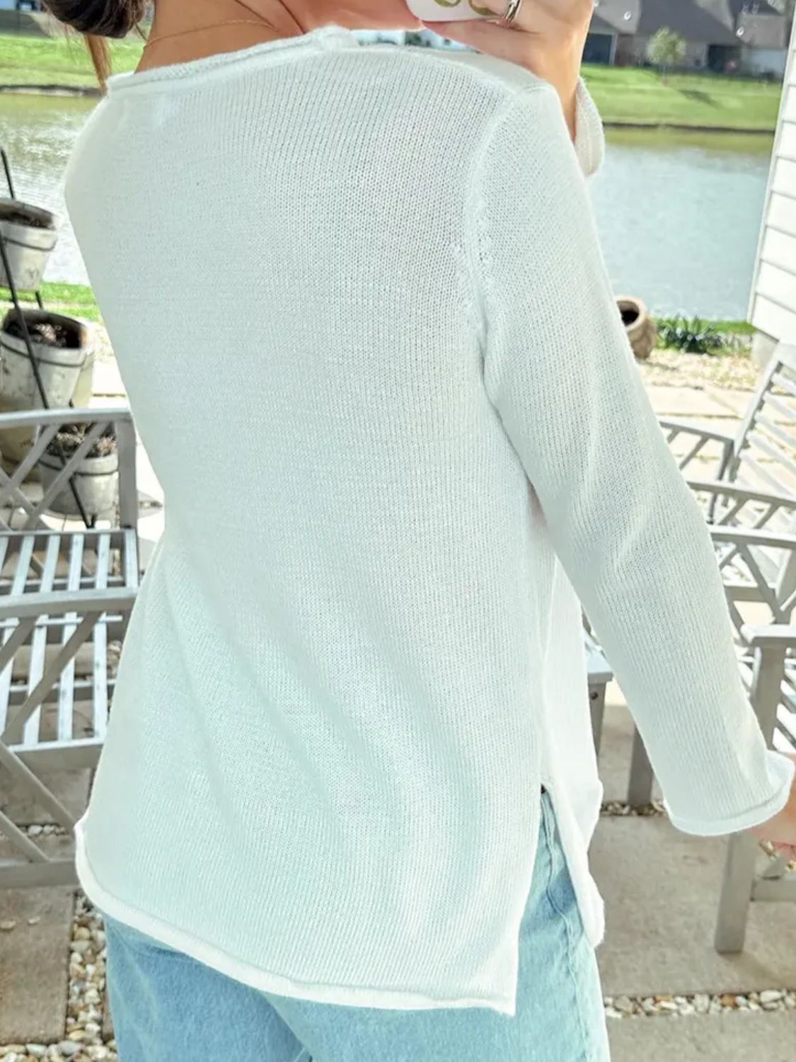 White knit jumper with raw hem detail, long sleeves, and side slits.