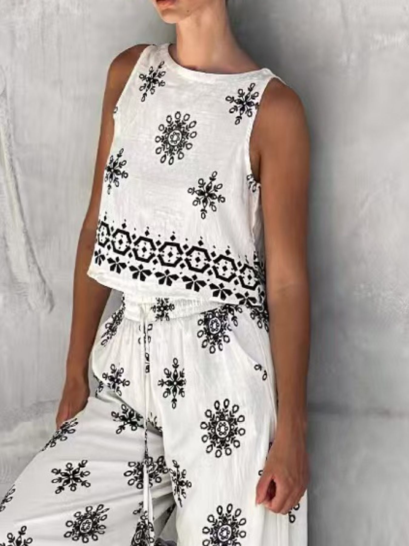 White two-piece set with medallion print, sleeveless crop top and drawstring pants.