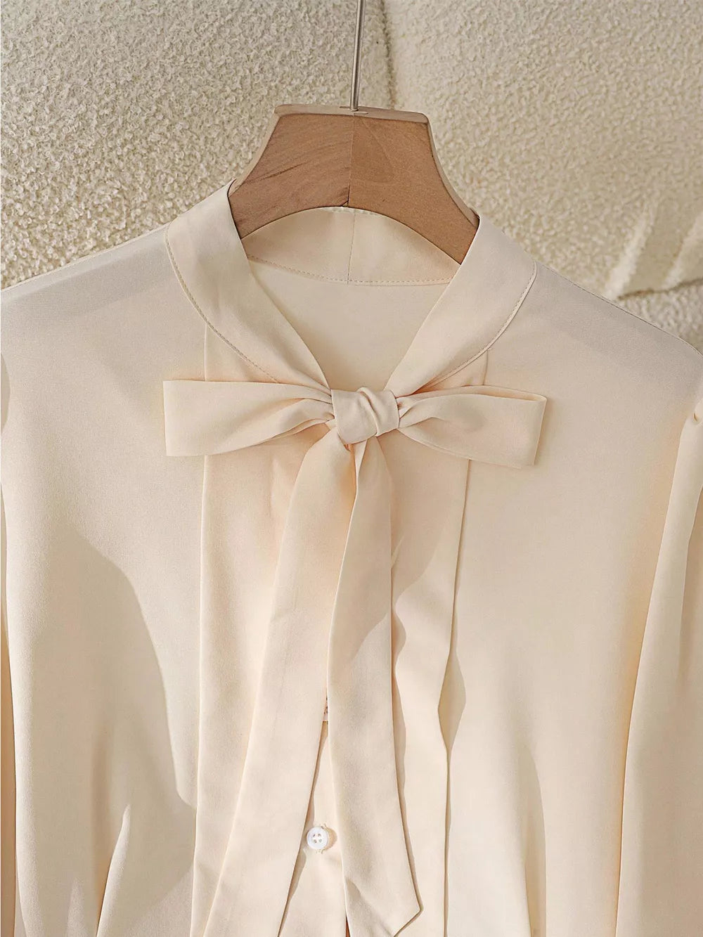 Apricot bow tie blouse with button-down front and long sleeves.
