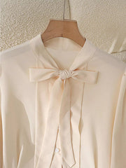 Apricot bow tie blouse with button-down front and long sleeves.
