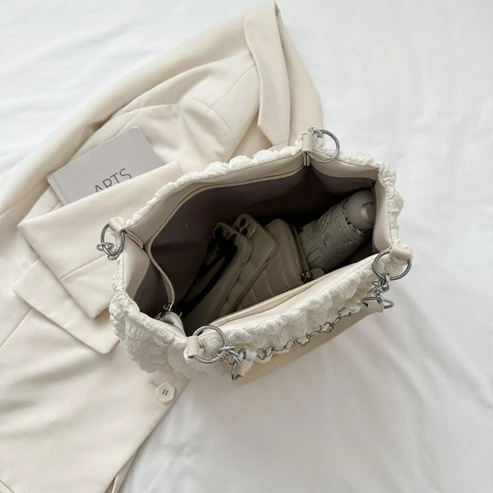 Textured grid pearl chain tote in ivory with ruffled trim and silver hardware.