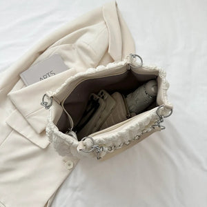 Textured grid pearl chain tote in ivory with ruffled trim and silver hardware.