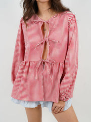 Red gingham tie-front peplum blouse with voluminous sleeves and a ruffled hem.