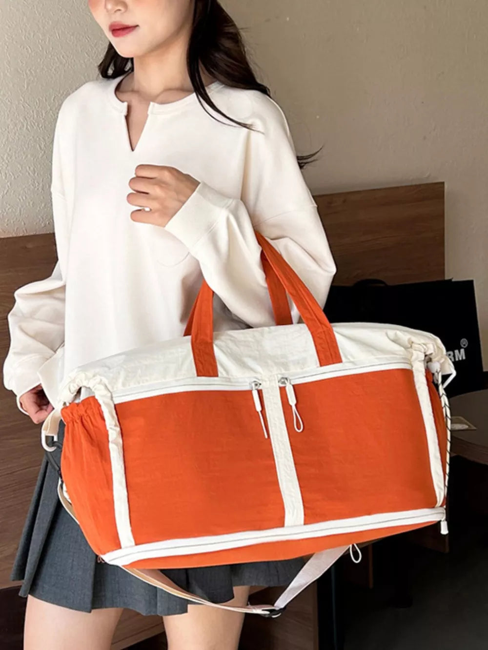 Vibrant color-block travel bag in orange and white with dual zip closures and adjustable strap.