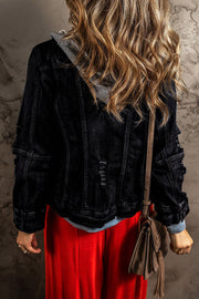 Black denim jacket with grey hooded layer, distressed details, buttoned cuffs.