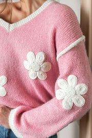 Pink knit sweater with white daisy appliqués and contrast trim.