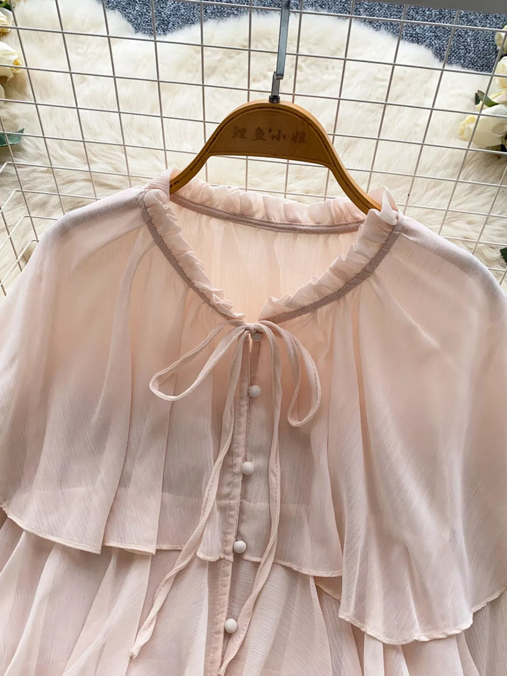 Pink chiffon blouse with ruffled neckline, tie detail, and button front.