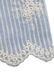 Blue and white striped peplum shirt with white floral embroidery and ruffled hem.