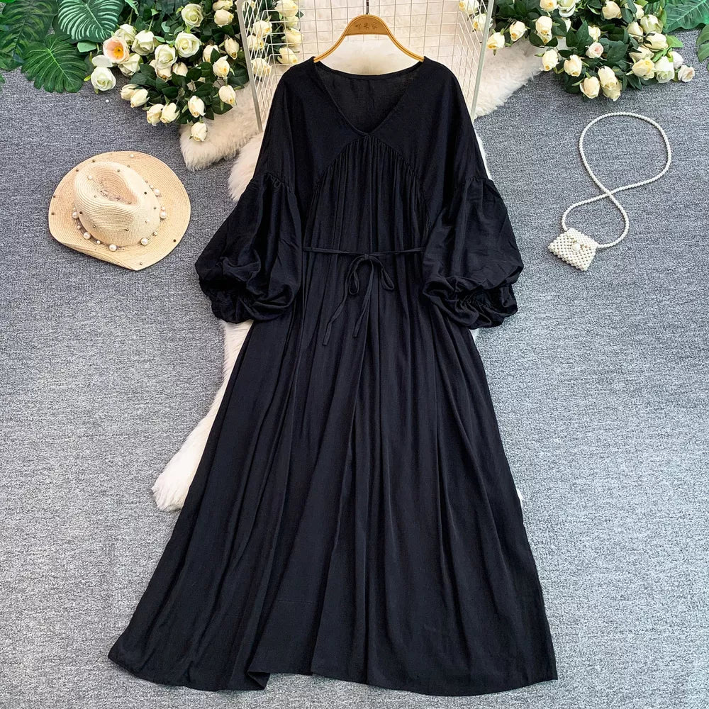 Black bohemian maxi dress with V-neck, cinched waist, and balloon sleeves.