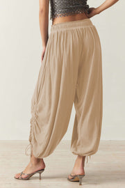 Tan gathered ankle-tie balloon trousers with cinched detailing and a drawstring hem.