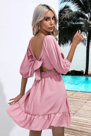 Blush pink mini dress with open back bow tie sleeves and ruffled hem.