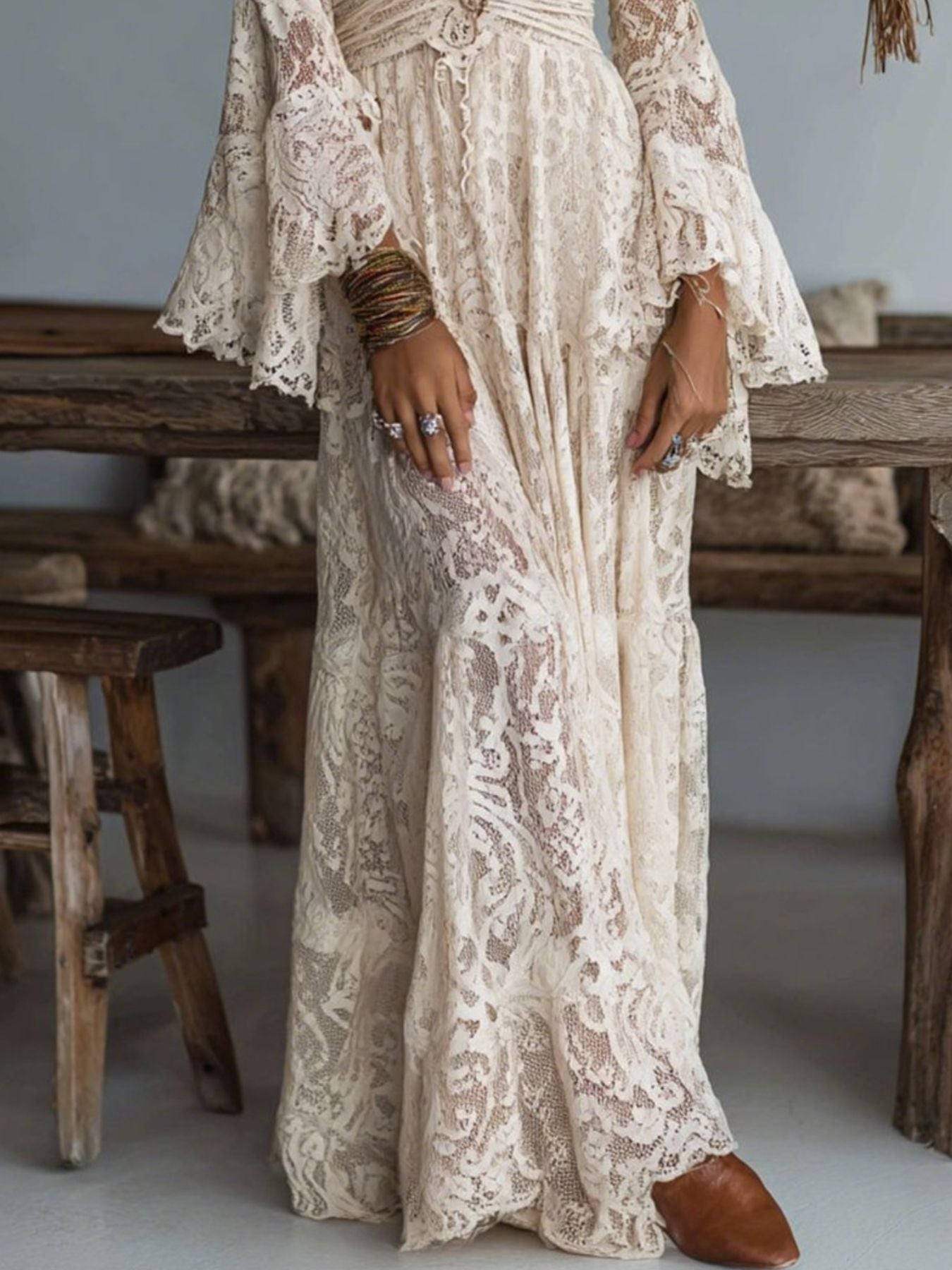 Cream lace maxi dress with deep V-neck, bell sleeves, and tiered skirt.