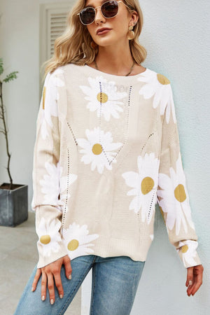 Beige intarsia knit sweater with white daisies, long sleeves, and open knit details.