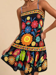 Black mini dress with vibrant floral print, yellow border trim, and spaghetti straps.